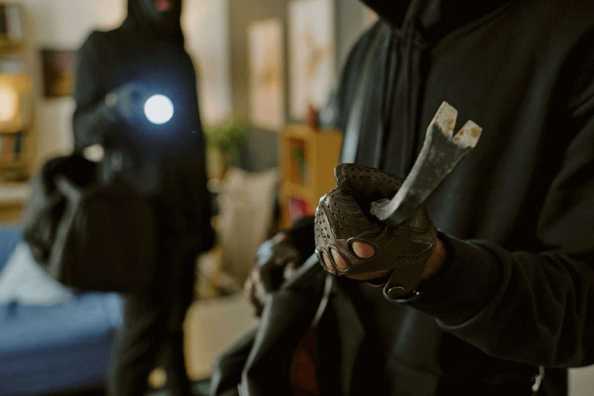 Intrusos enmascarados con una linterna y una palanca dentro de una casa