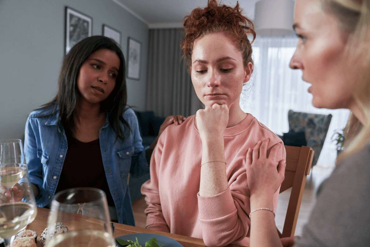 Tres mujeres en una conversación seria alrededor de una mesa