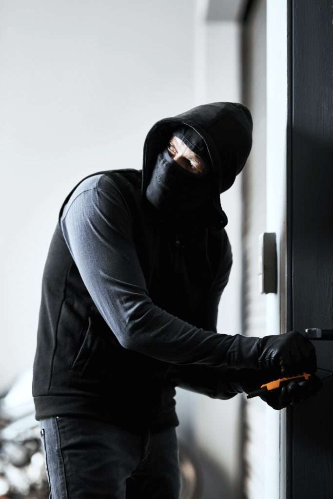 Un ladrón enmascarado abriendo una puerta