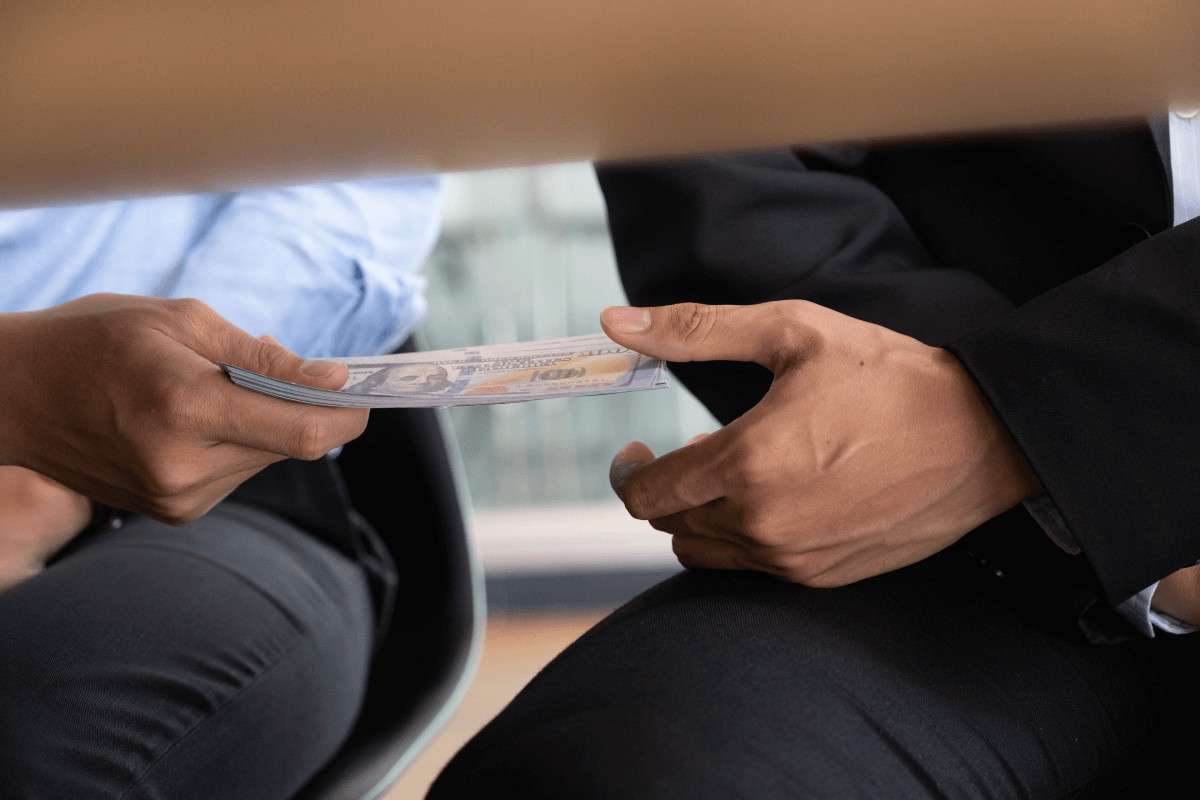 Dinero pasando por debajo de una mesa entre dos personas
