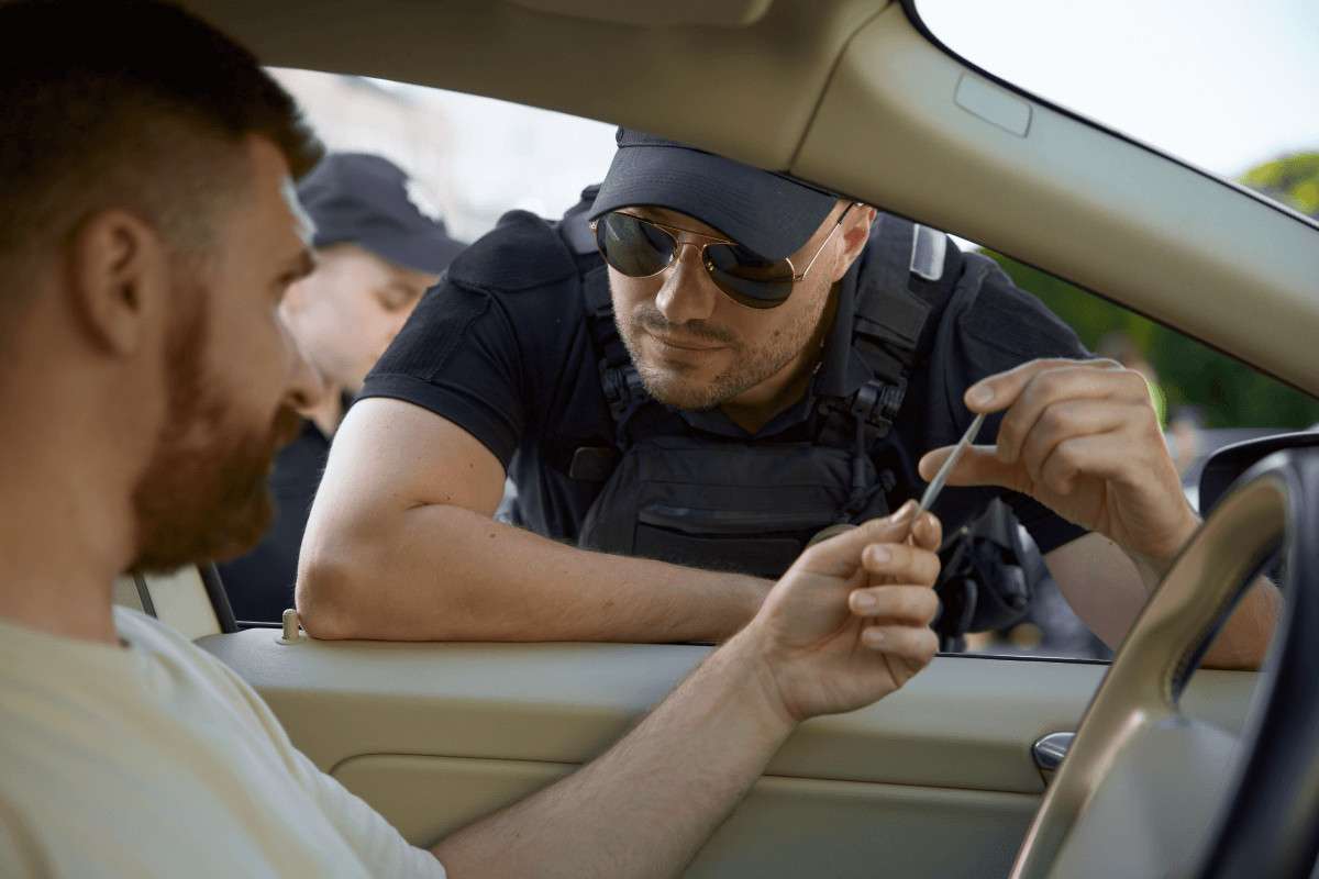 Un agente de policía en la ventanilla de un coche con un alcoholímetro para el conductor