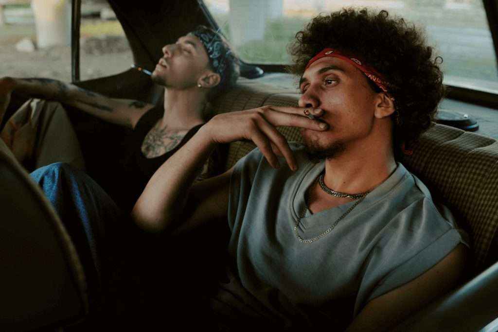 Dos jóvenes fumando en el asiento trasero de un coche