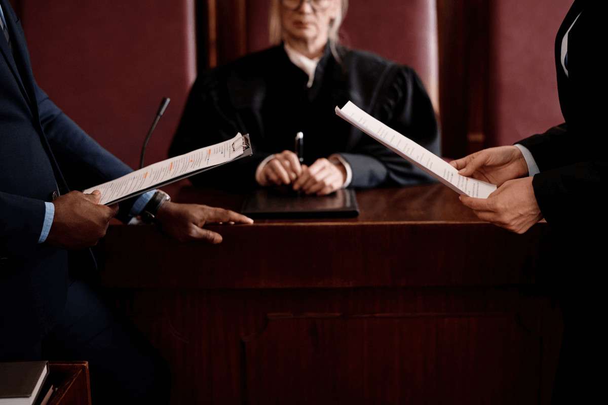 Dos personas entregando papeles a un juez en el estrado