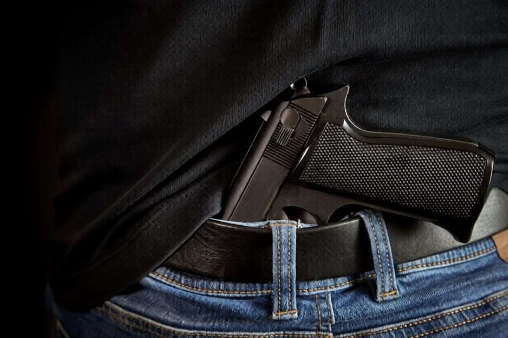 Una pistola metida en la cintura de los jeans de un hombre