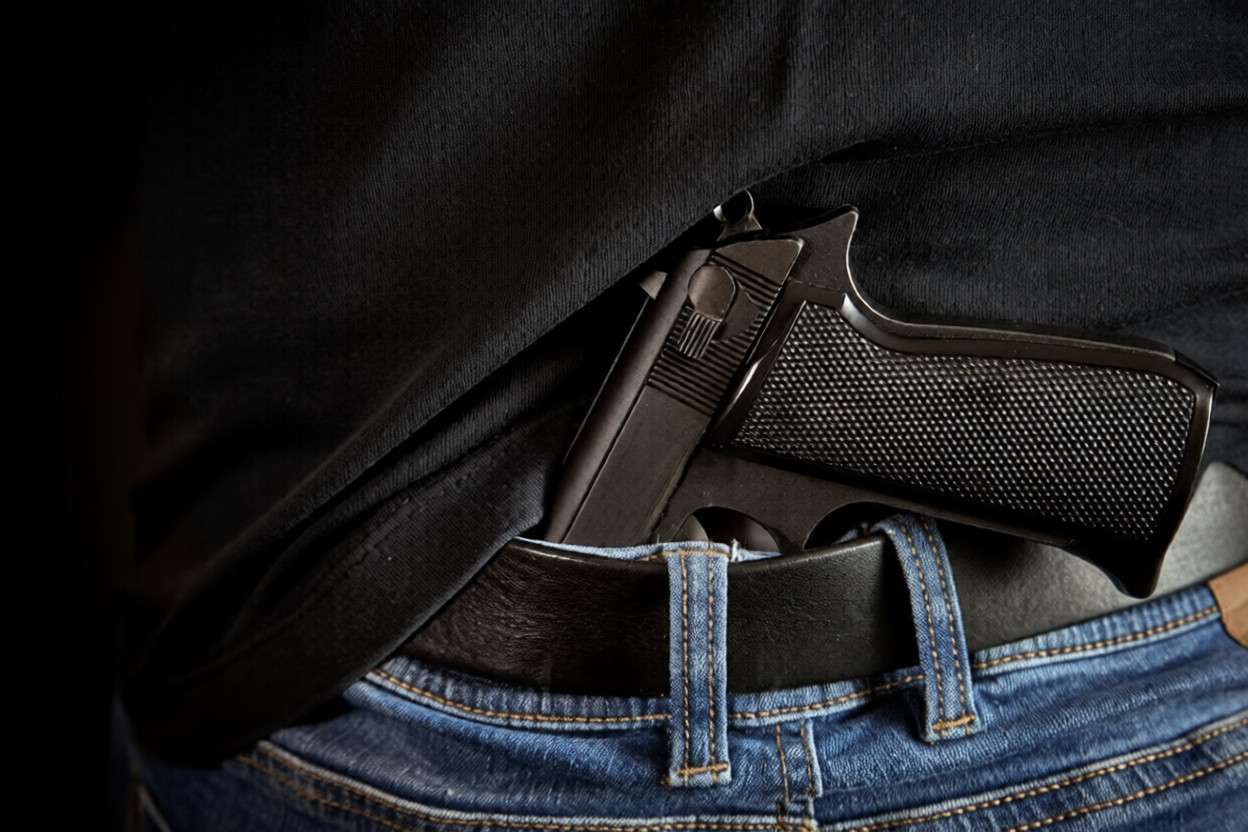 Una pistola metida en la cintura de los jeans de un hombre