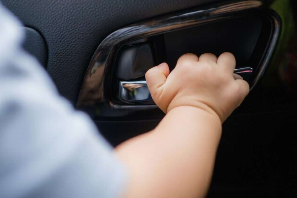 La mano de un niño abriendo la puerta de un coche