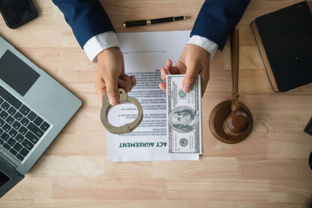 Unas manos pasando esposas y dinero sobre un escritorio con un contrato