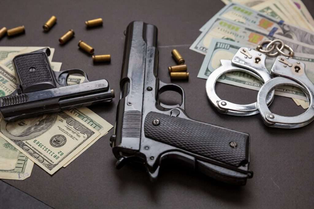 Dos pistolas, balas, dinero y unas esposas sobre una mesa
