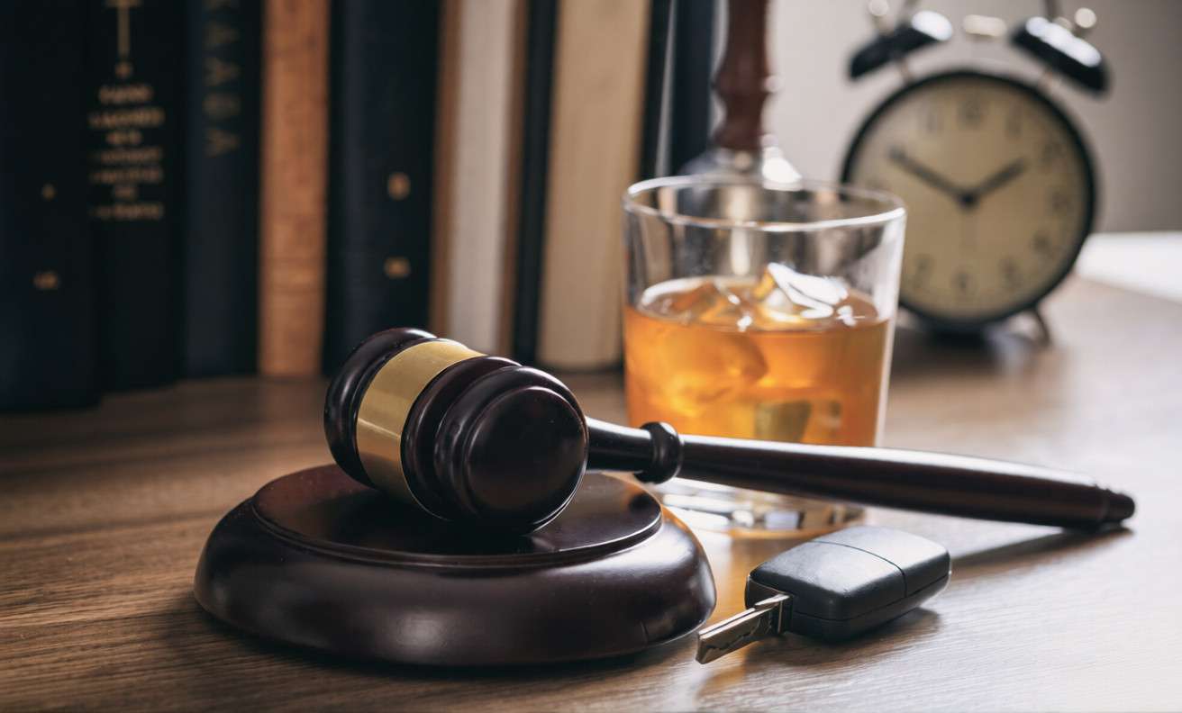 Un mazo, las llaves de un coche y un vaso de whisky sobre un escritorio