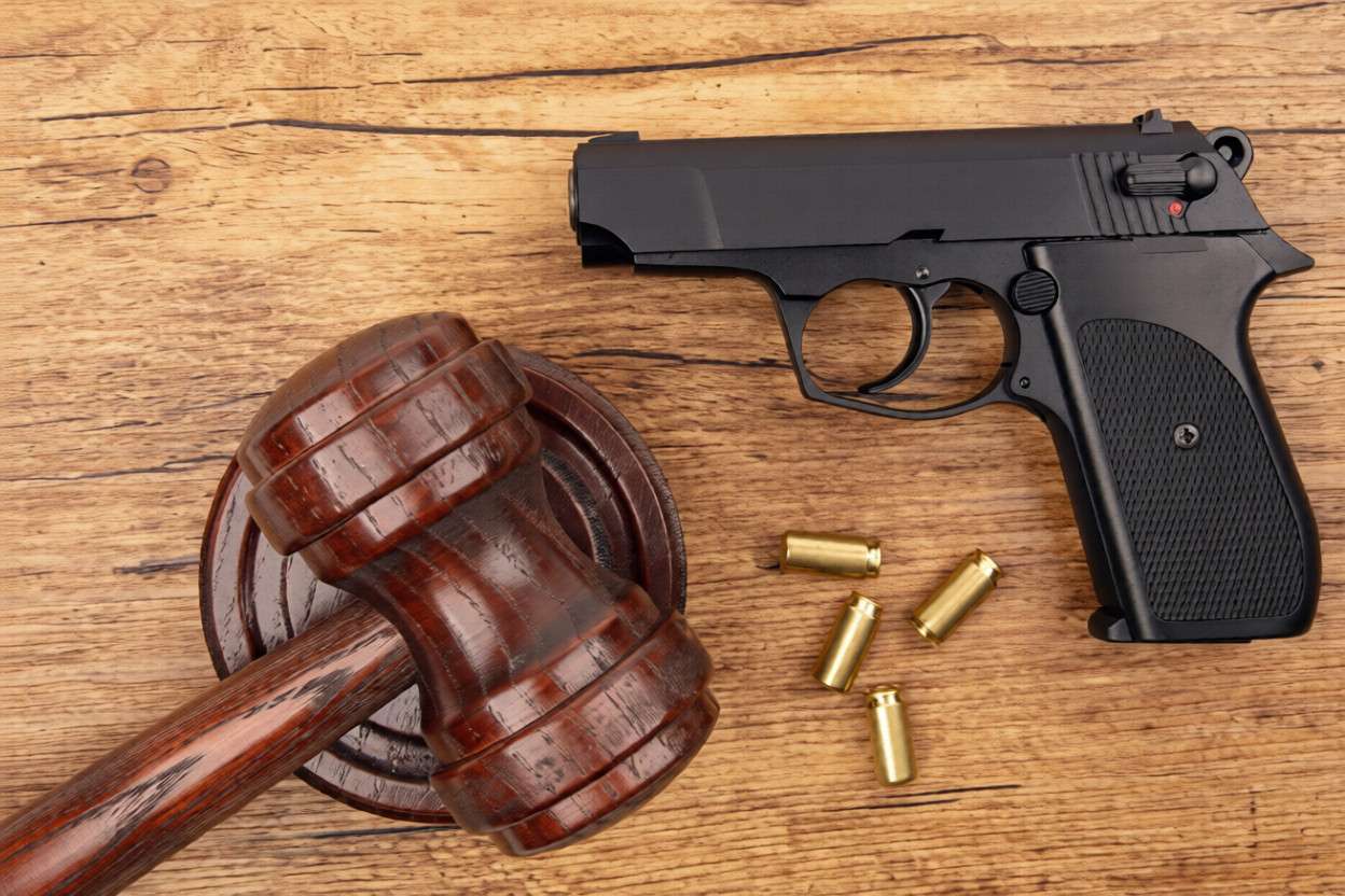 Una pistola, balas y un mazo sobre una mesa de madera