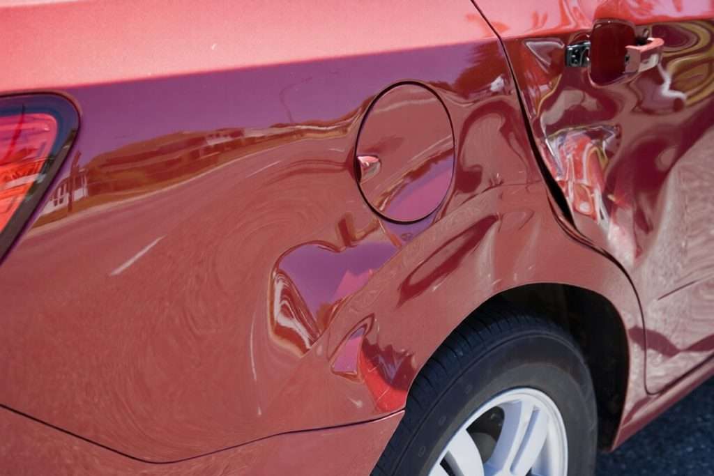 Una abolladura en el costado de un coche rojo