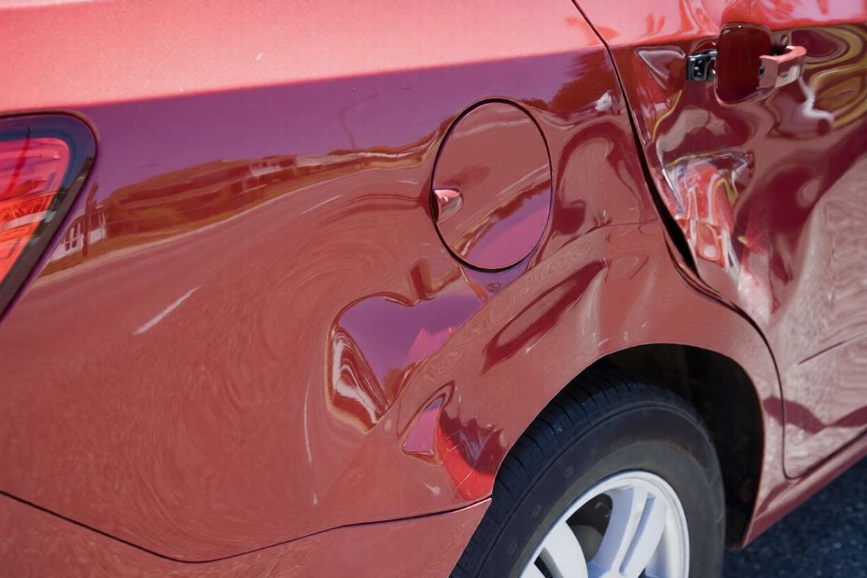 Una abolladura en el costado de un coche rojo